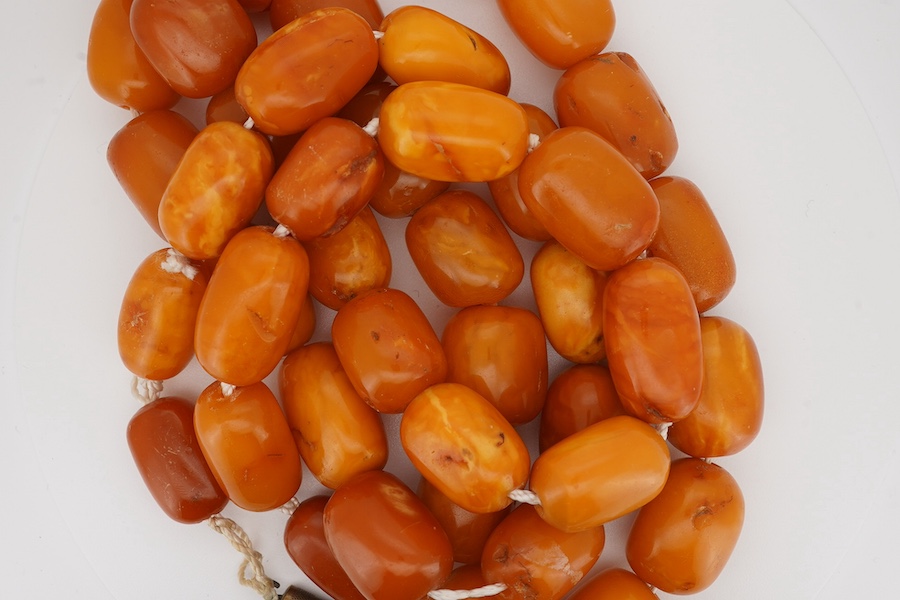 A single strand oval and barrel shaped amber bead necklace, 90cm, gross weight 102 grams. Condition - poor to fair